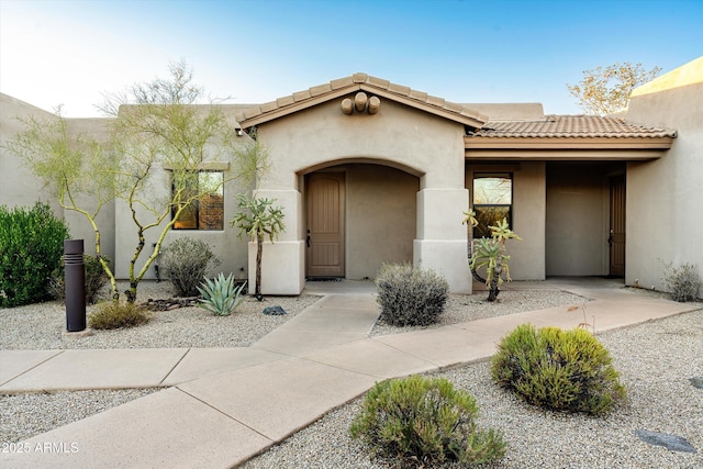 entrance to property with a tile roof and stucco siding