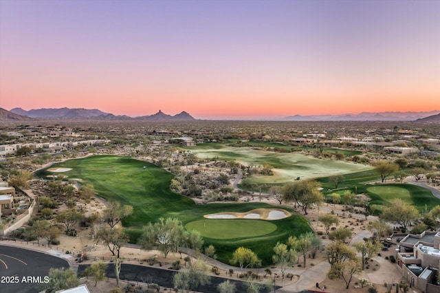 aerial view at dusk with view of golf course and a mountain view