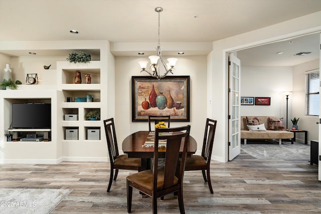 dining space with visible vents, a notable chandelier, baseboards, and wood finished floors