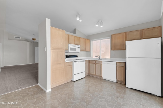 kitchen with light brown cabinetry, vaulted ceiling, sink, and white appliances