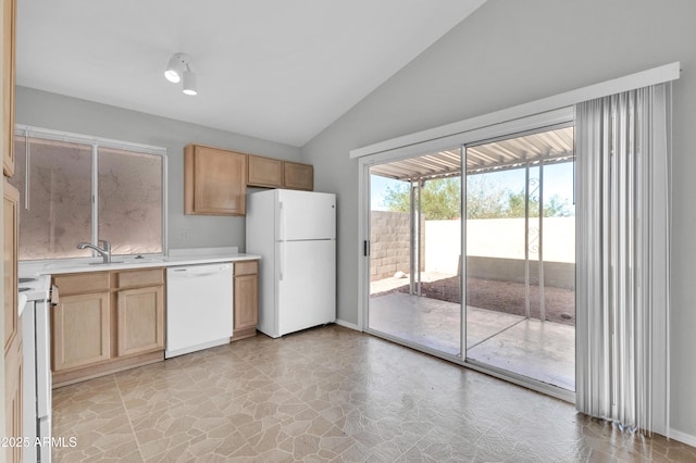 kitchen with lofted ceiling, light brown cabinets, sink, and white appliances