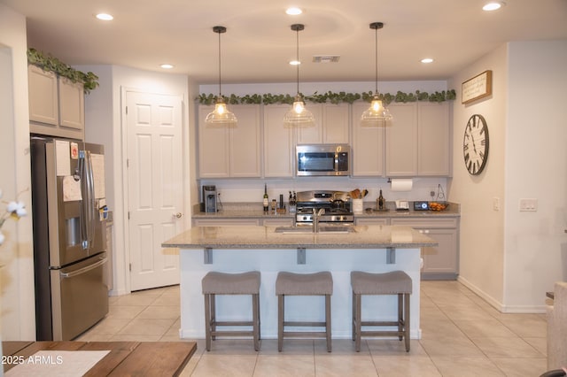 kitchen with stainless steel appliances, a center island with sink, and decorative light fixtures