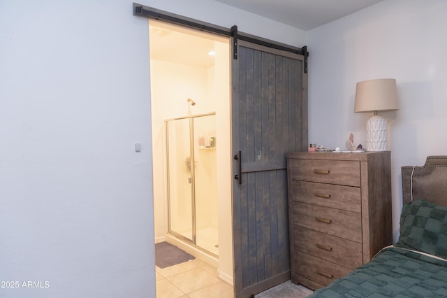 tiled bedroom featuring ensuite bathroom and a barn door