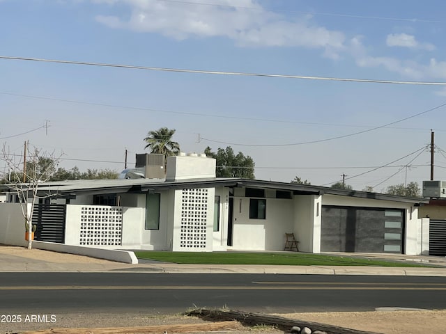 contemporary home with central air condition unit and stucco siding