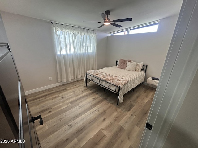 bedroom with a ceiling fan, light wood-type flooring, and baseboards