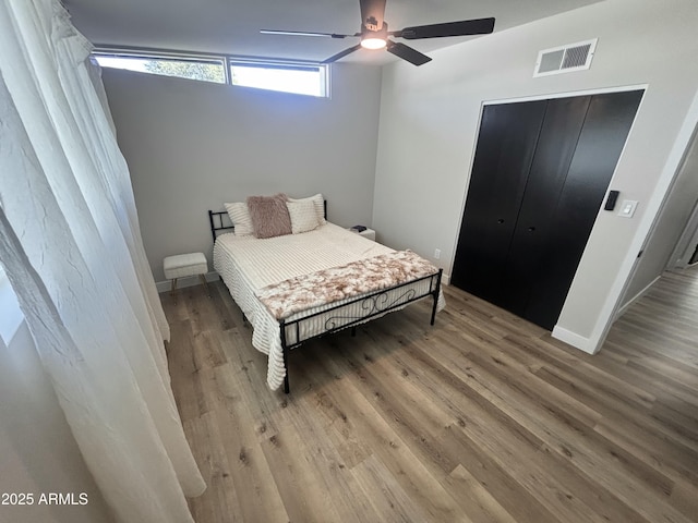 bedroom with a closet, wood finished floors, visible vents, and a ceiling fan