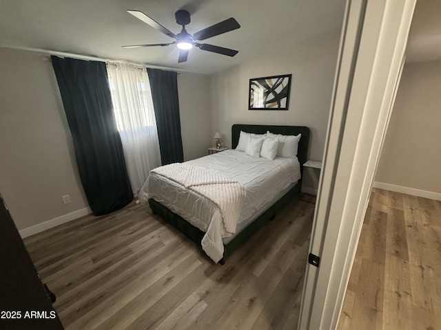 bedroom featuring wood finished floors, a ceiling fan, and baseboards