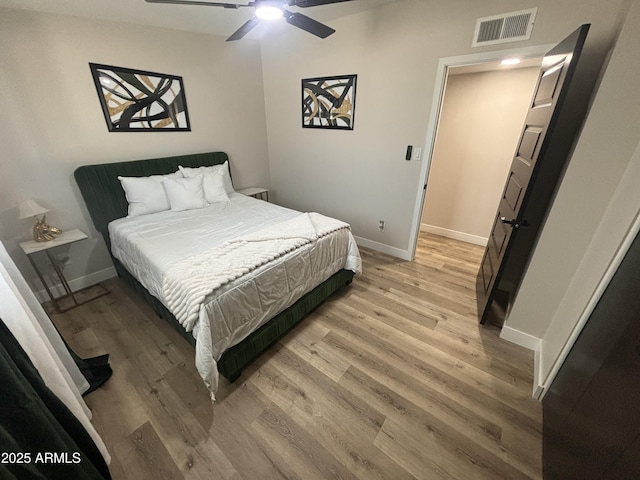 bedroom featuring light wood finished floors, a ceiling fan, visible vents, and baseboards