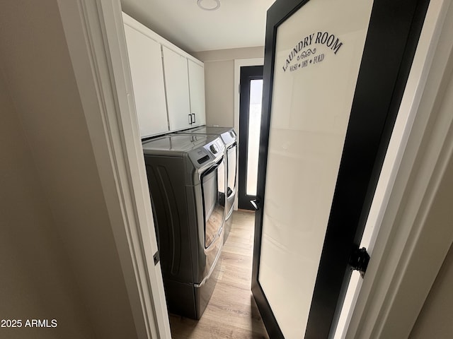 clothes washing area with light wood-type flooring, cabinet space, and separate washer and dryer