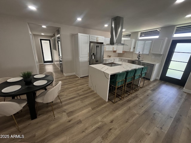 kitchen with island range hood, a sink, light wood-style floors, appliances with stainless steel finishes, and a center island