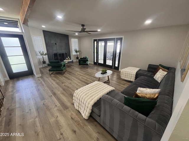 living room featuring baseboards, wood finished floors, a fireplace, beam ceiling, and recessed lighting