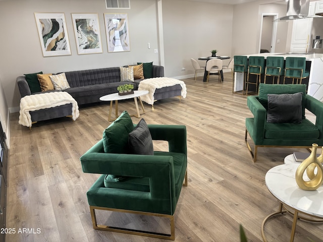 living area featuring baseboards, visible vents, and light wood finished floors