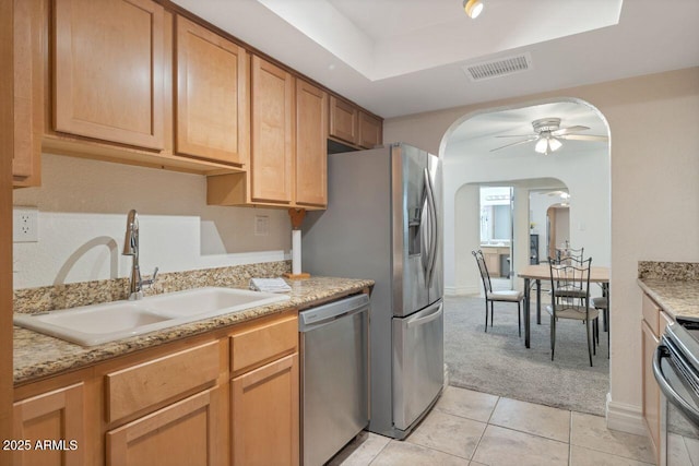 kitchen with light tile patterned flooring, sink, ceiling fan, stainless steel appliances, and light stone countertops