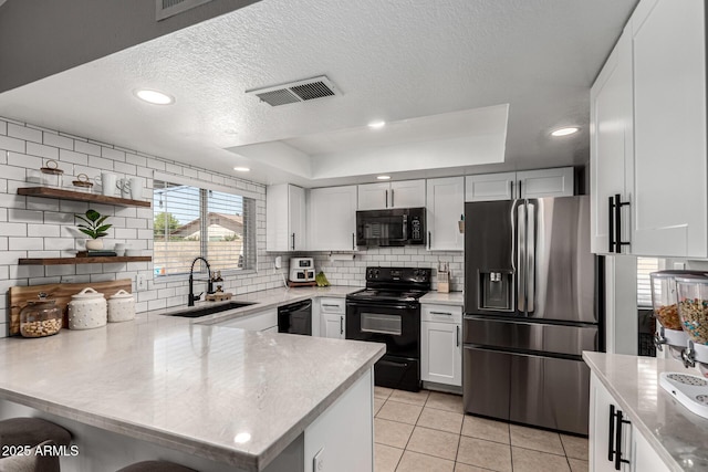 5302 W Poinsettia Dr, Glendale, AZ 85304 - kitchen with black appliances, a peninsula, light tile patterned floors, backsplash, and a tray ceiling