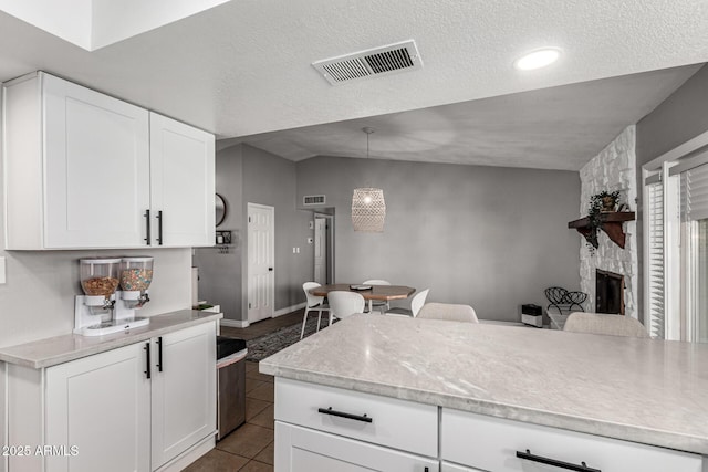5302 W Poinsettia Dr, Glendale, AZ 85304 - kitchen featuring a textured ceiling, white cabinetry, a fireplace, hanging light fixtures, and dark tile patterned floors