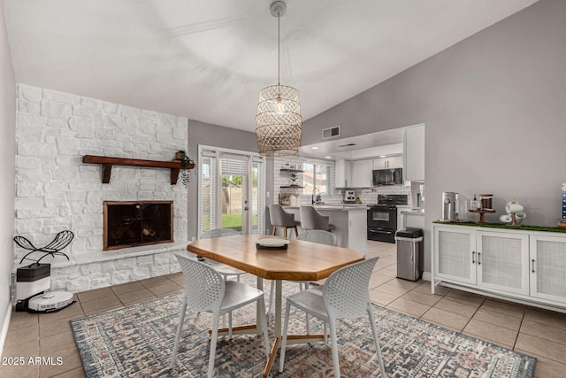 5302 W Poinsettia Dr, Glendale, AZ 85304 - dining room with light tile patterned floors, vaulted ceiling, a fireplace, and a chandelier