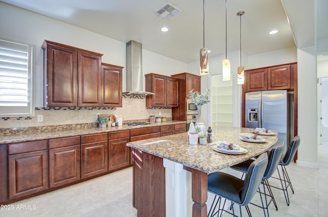 3753 E Ellis St, Mesa, AZ 85205 - kitchen with visible vents, a kitchen island, wall chimney exhaust hood, light stone counters, and appliances with stainless steel finishes