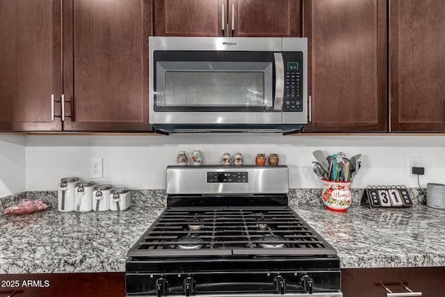 kitchen with dark brown cabinetry, stainless steel appliances, and light stone counters