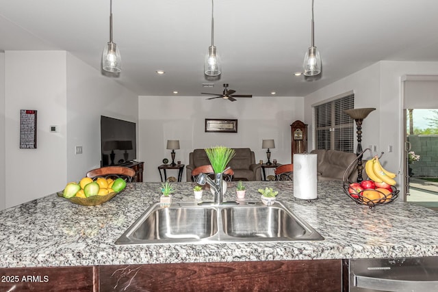 kitchen featuring a sink, stone counters, a ceiling fan, and open floor plan