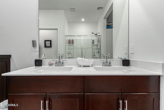 bathroom featuring visible vents, a sink, double vanity, and a shower stall