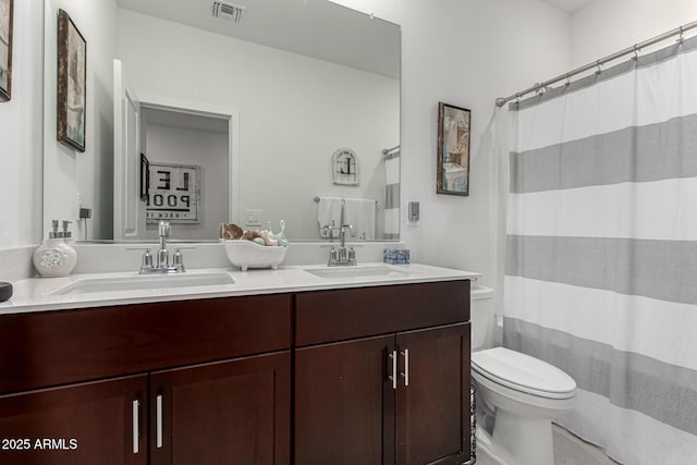 full bath featuring toilet, a sink, double vanity, and visible vents