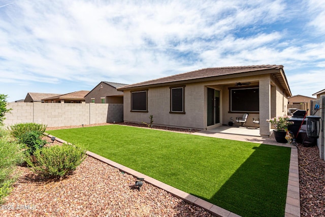 rear view of house featuring stucco siding, a fenced backyard, ceiling fan, a yard, and a patio area