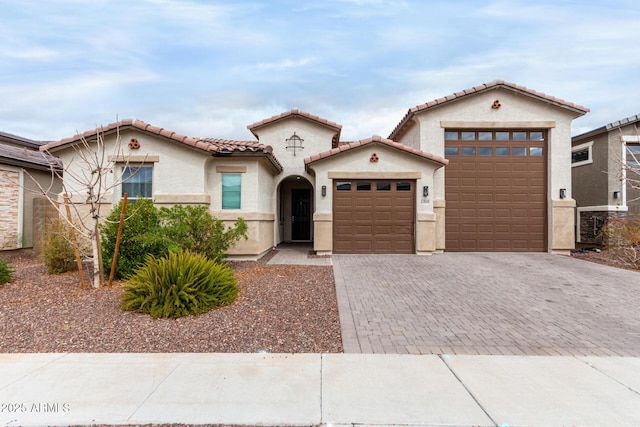 mediterranean / spanish-style house featuring a tile roof, an attached garage, driveway, and stucco siding