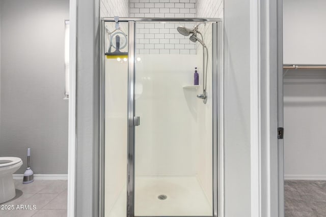 bathroom with tile patterned floors, toilet, and a shower stall