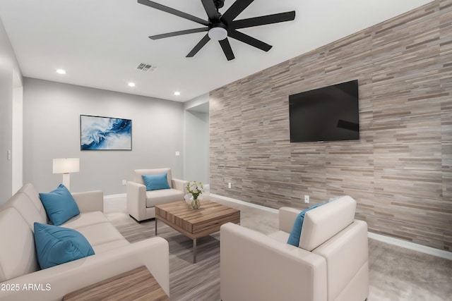 living room with visible vents, an accent wall, ceiling fan, recessed lighting, and tile walls