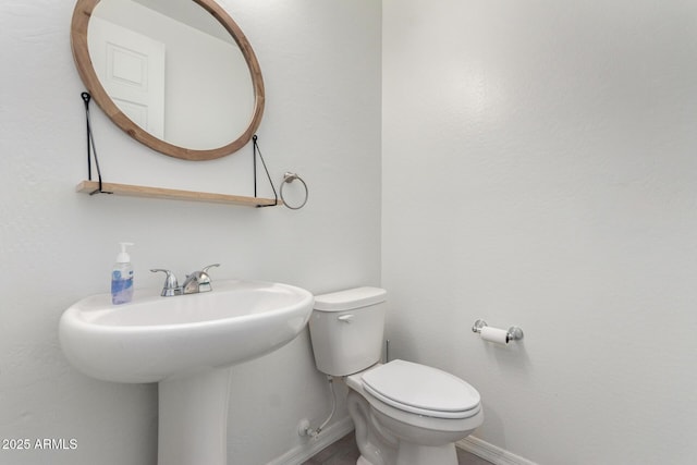 half bathroom featuring a sink, baseboards, and toilet