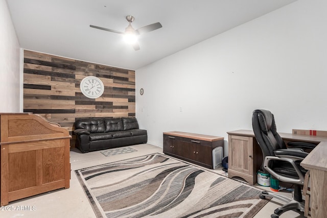 office area with a ceiling fan, concrete flooring, wood walls, and an accent wall