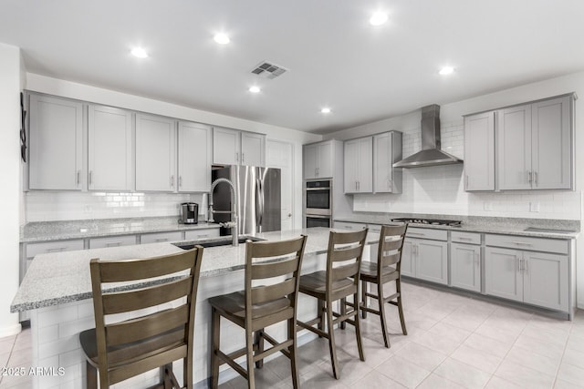 kitchen featuring wall chimney exhaust hood, visible vents, and gray cabinetry