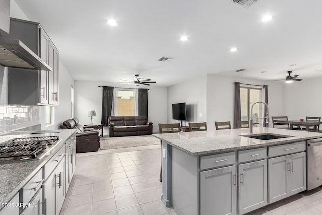 kitchen featuring visible vents, ceiling fan, gray cabinets, wall chimney exhaust hood, and a sink