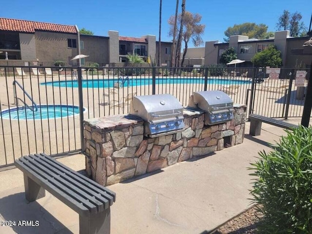 view of patio with exterior kitchen, a community pool, and grilling area