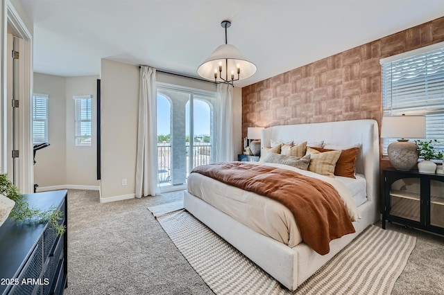 carpeted bedroom featuring access to exterior and a notable chandelier