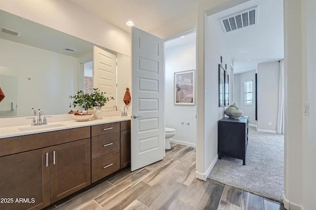 bathroom with hardwood / wood-style flooring, vanity, and toilet