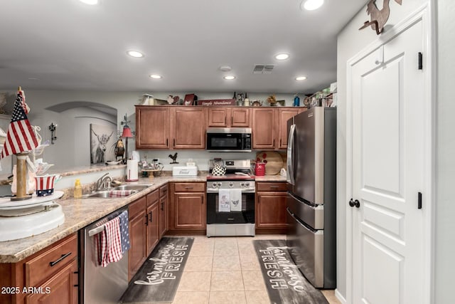 14112 W Larkspur Dr, Surprise, AZ 85379 - kitchen with stainless steel appliances, a sink, brown cabinets, arched walkways, and recessed lighting