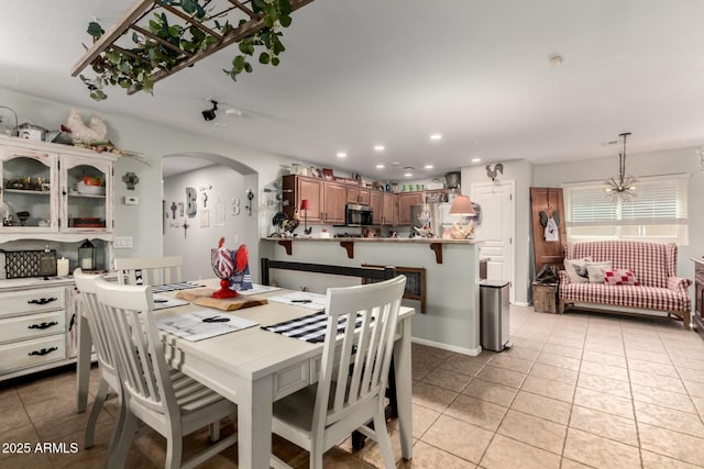 14112 W Larkspur Dr, Surprise, AZ 85379 - dining area with light tile patterned flooring, arched walkways, recessed lighting, and a chandelier