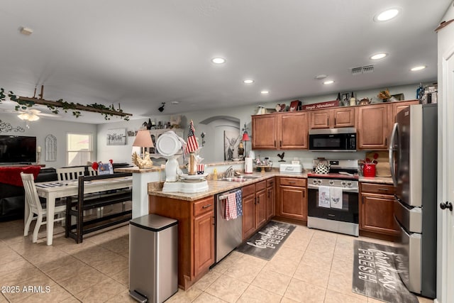 14112 W Larkspur Dr, Surprise, AZ 85379 - kitchen featuring appliances with stainless steel finishes, brown cabinetry, light tile patterned floors, recessed lighting, and a sink