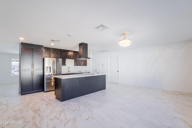 kitchen with stainless steel refrigerator with ice dispenser, sink, an island with sink, exhaust hood, and stovetop