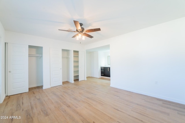 unfurnished bedroom with two closets, ceiling fan, and light hardwood / wood-style flooring