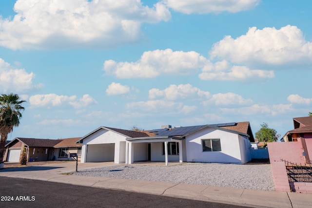 ranch-style house with a garage and solar panels