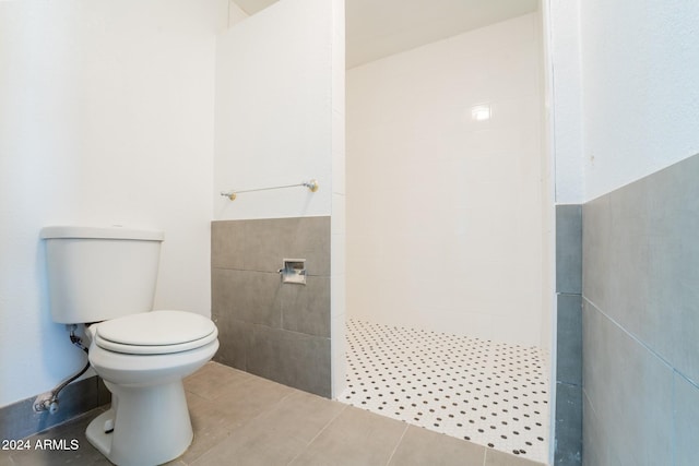 bathroom featuring tile patterned flooring, toilet, and tiled shower