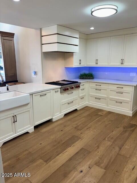 kitchen with dark hardwood / wood-style flooring, sink, white cabinets, and stainless steel gas cooktop