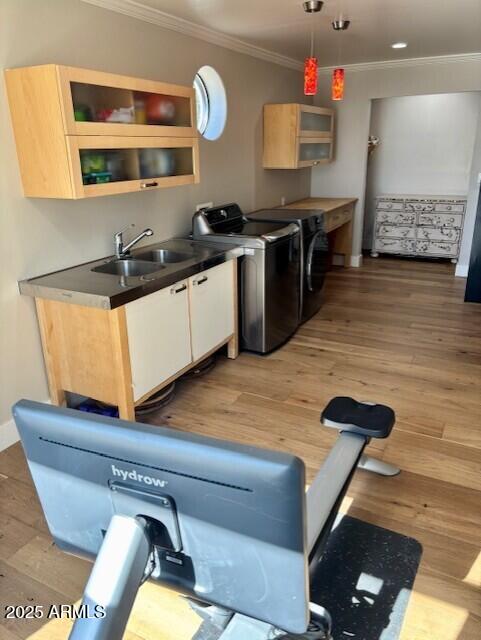 kitchen featuring sink, crown molding, light brown cabinets, pendant lighting, and washing machine and dryer