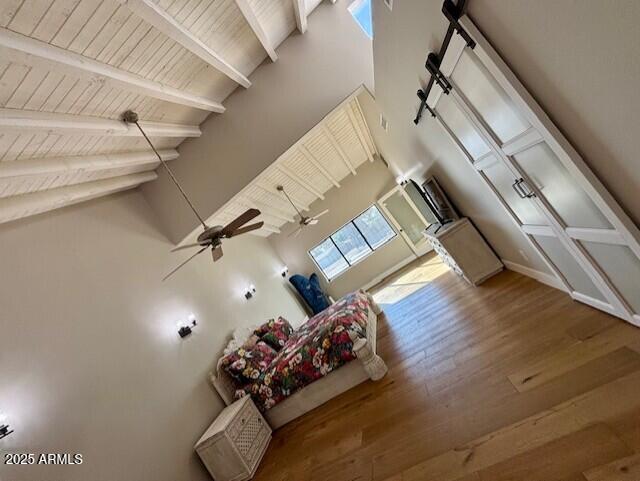 unfurnished living room with ceiling fan, hardwood / wood-style floors, wooden ceiling, and beam ceiling