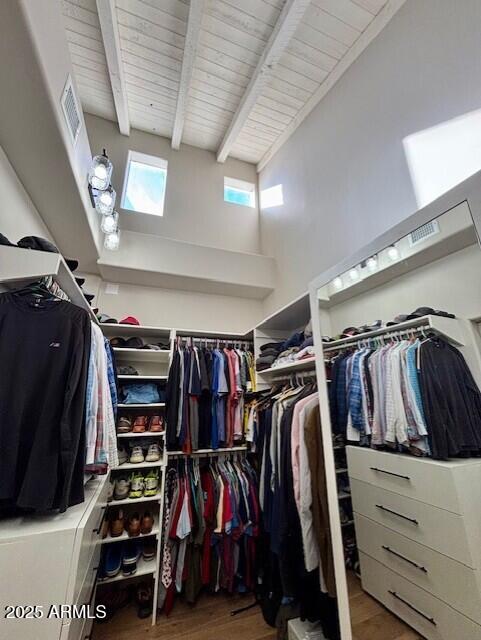 walk in closet featuring beamed ceiling and hardwood / wood-style flooring