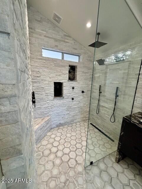 bathroom with vaulted ceiling and tiled shower