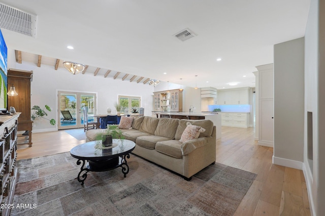 living room with french doors, sink, and light hardwood / wood-style floors