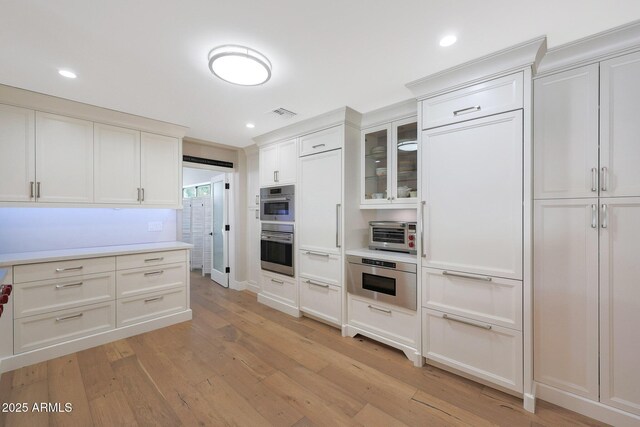 kitchen with white cabinetry, light hardwood / wood-style flooring, and stainless steel double oven